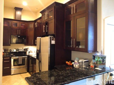 A kitchen with a black granite counter top and wooden cabinets.