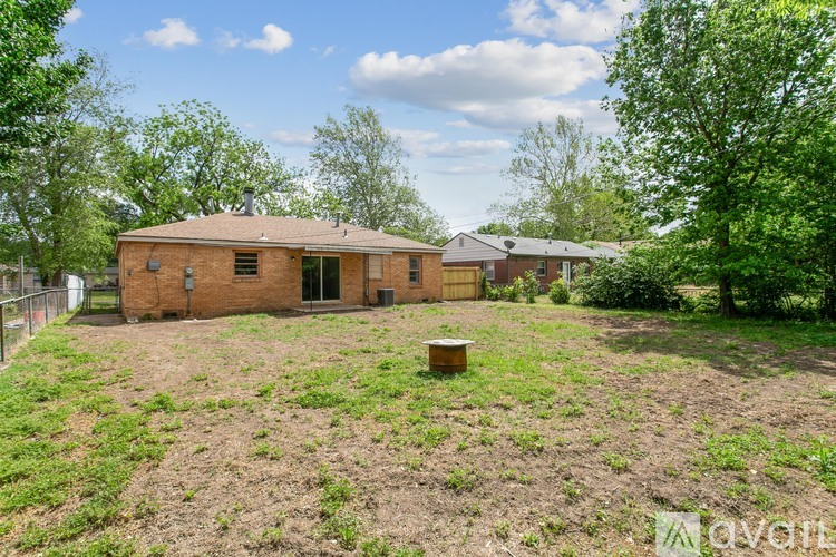 A beehive is placed in the middle of a grassy yard in front of a brick house.