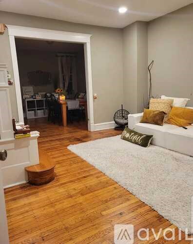 A living room with a white couch and a grey rug.