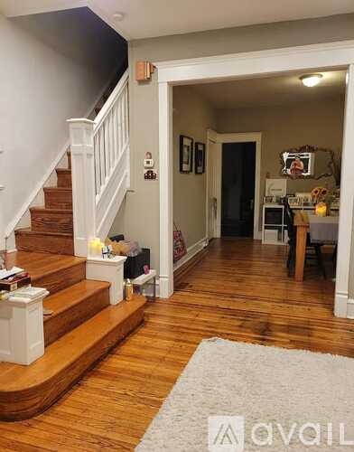 A hallway with a staircase and a rug on the floor.