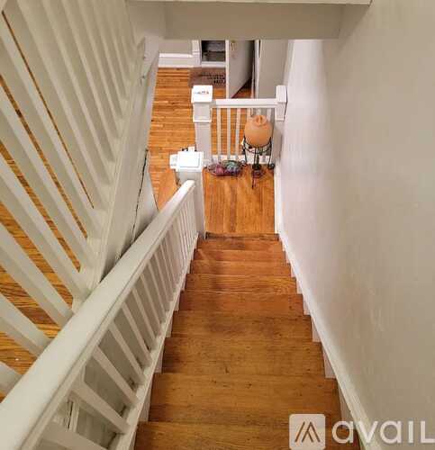 A staircase with white railings leads to a living room.