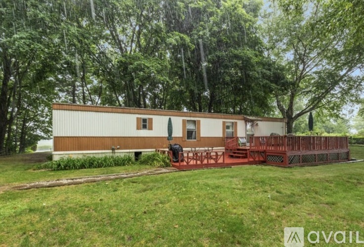 A house with a red deck is surrounded by trees.