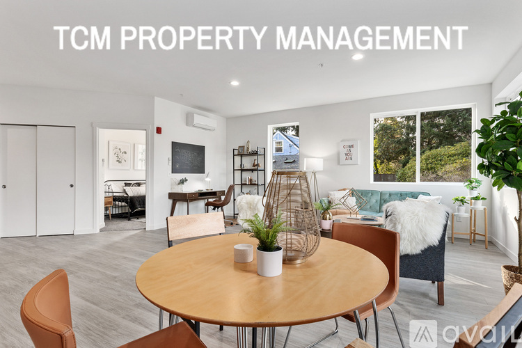 A living room with a table and chairs and a sign that says TCM PROPERTY MANAGEMENT.