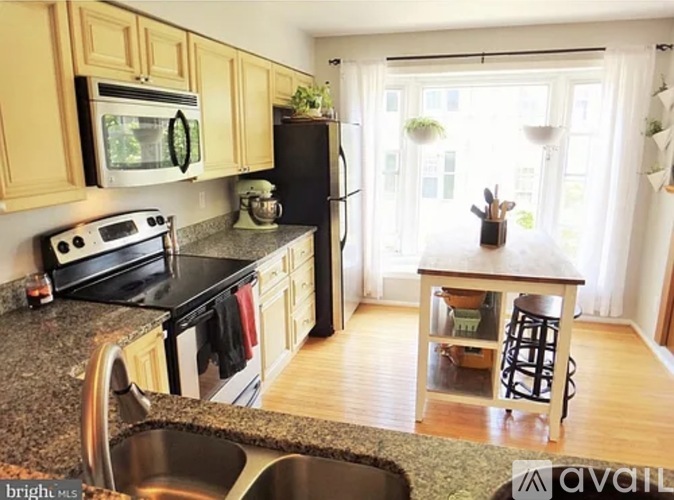 A kitchen with wooden cabinets and a black refrigerator.