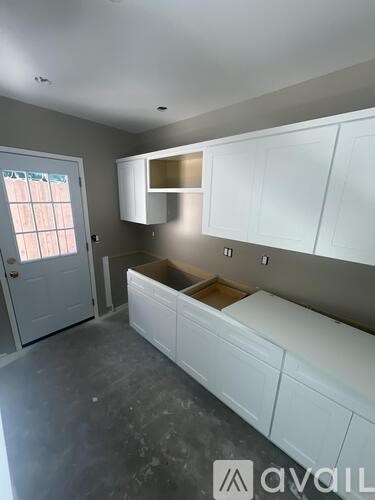 A kitchen with white cabinets and a window.