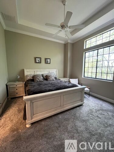 A bedroom with a large bed and a ceiling fan.