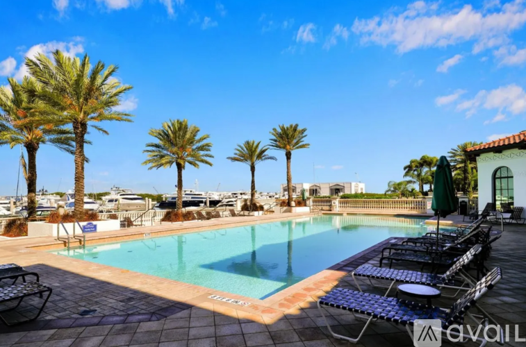 A pool surrounded by palm trees and lounge chairs.
