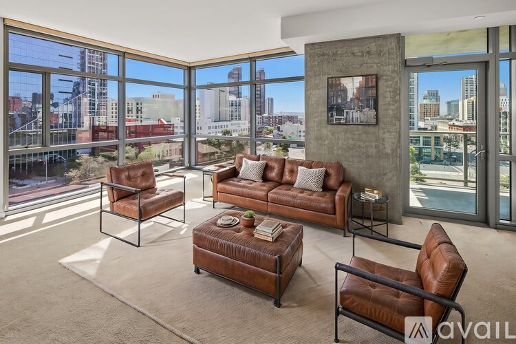 A living room with brown leather furniture and a view of the city.