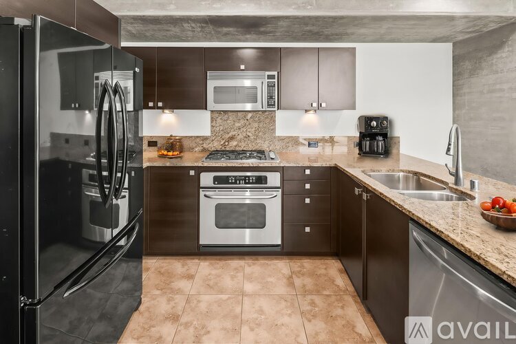 A modern kitchen with a black refrigerator and stainless steel appliances.