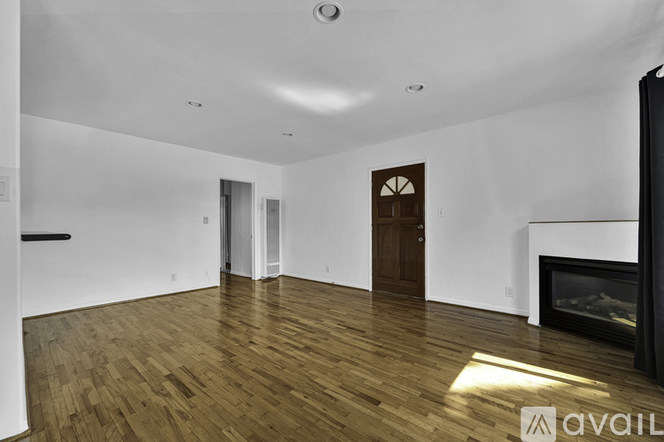 A spacious room with wooden flooring and a fireplace.