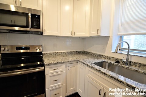A kitchen with white cabinets and a black stove top oven.