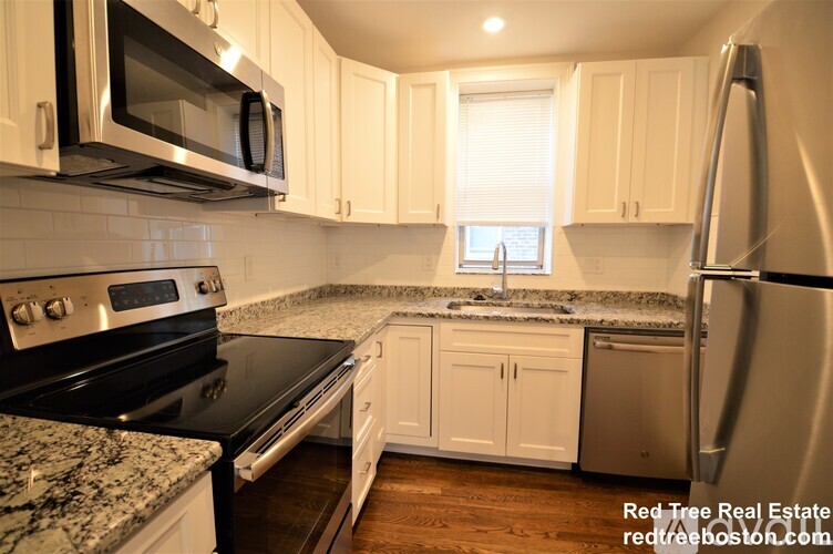 A kitchen with white cabinets and a granite countertop.