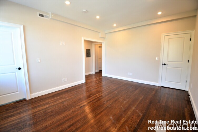 A spacious room with wooden floors and white walls.