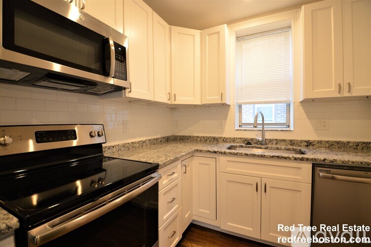 A kitchen with white cabinets and black appliances.