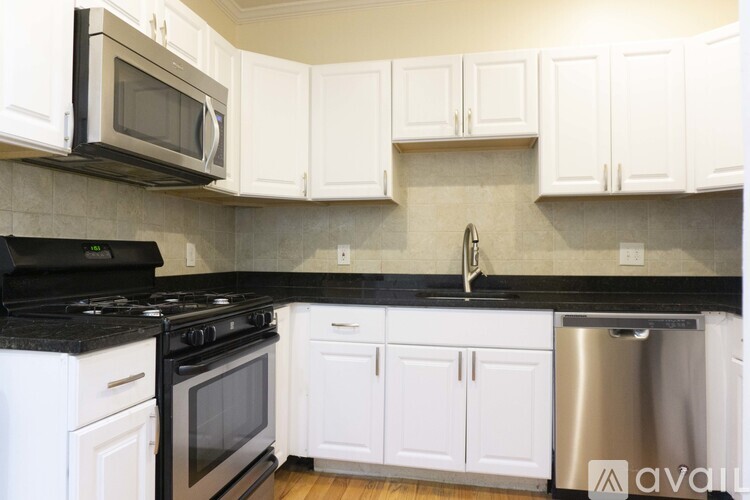 A kitchen with white cabinets and black countertops.