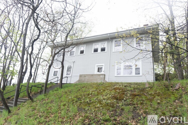 A house with a grey roof and white walls is surrounded by trees.