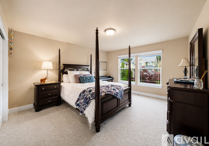 A bedroom with a four poster bed and a window showing a view of a house.