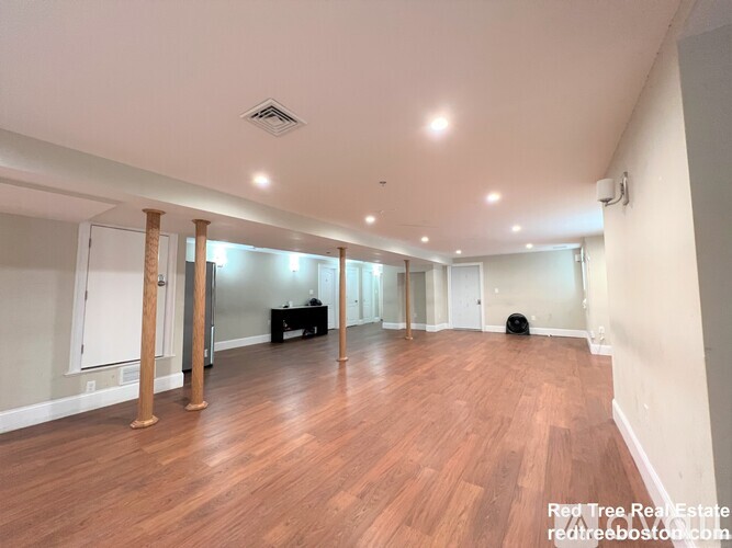 A spacious room with wooden floors and white walls.