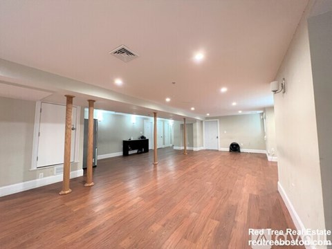 A spacious room with wooden floors and white walls.