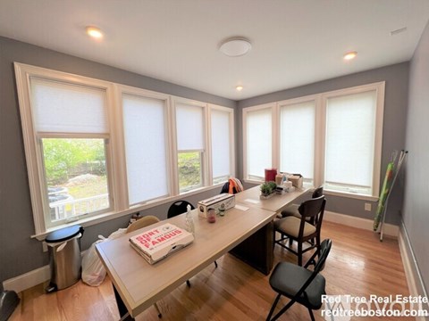 A dining room with a table and chairs and a window.
