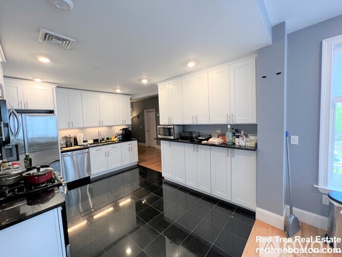 A kitchen with white cabinets and black countertops.