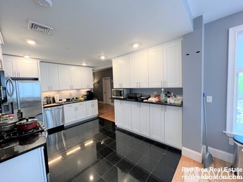 A kitchen with white cabinets and black countertops.