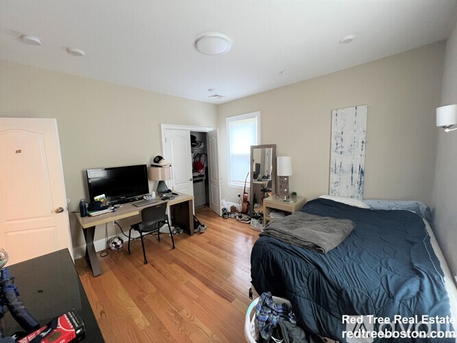 A bedroom with a bed, desk, and chair.