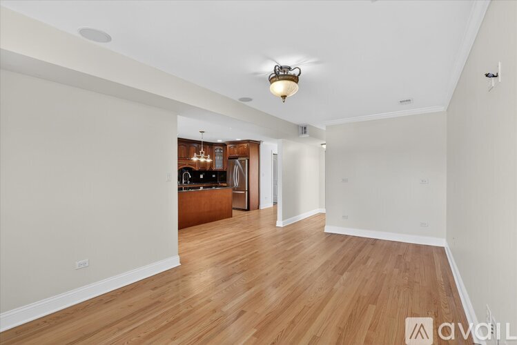 A spacious room with wooden flooring and a light fixture on the ceiling.