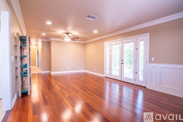 A spacious room with wooden floors and a ceiling fan.