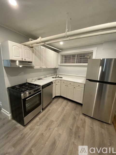A kitchen with white cabinets and a stainless steel refrigerator.
