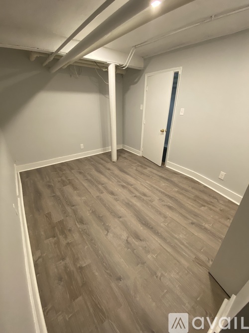 A room with a wooden floor and a door on the right side.