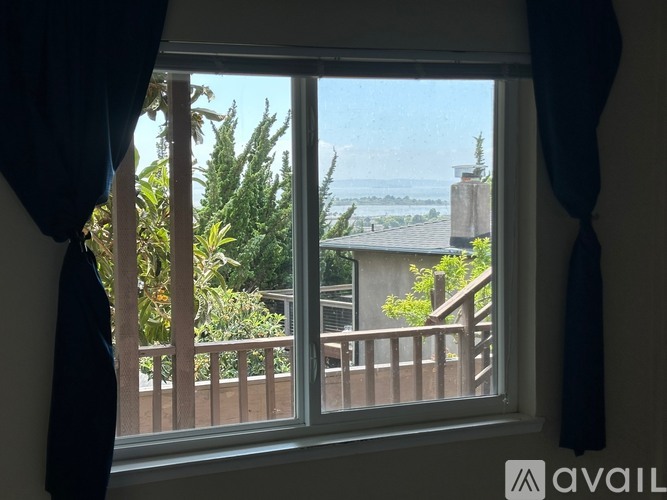 A window with a view of a balcony and trees.