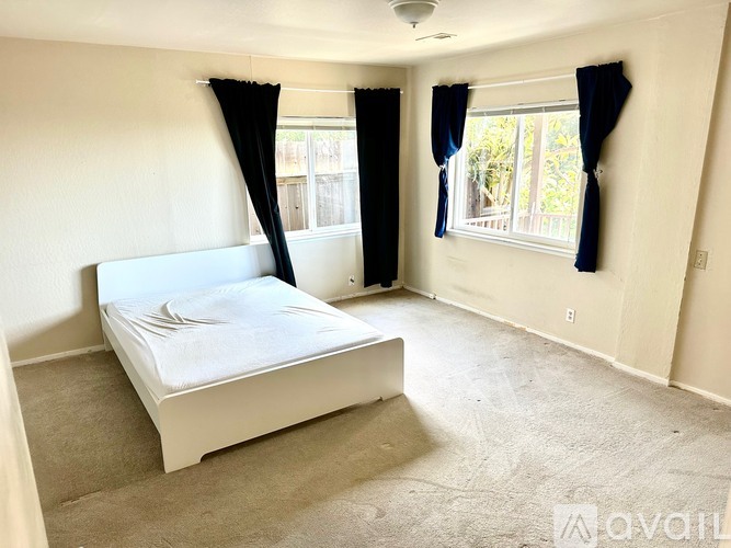 A bedroom with a white bed and carpeted floor.