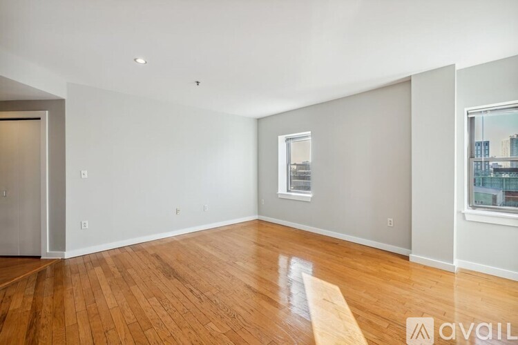 A spacious room with wooden floors and a window showing a cityscape.