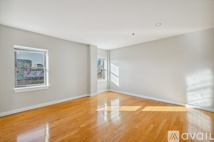 A room with wooden floors and a window showing a cityscape outside.