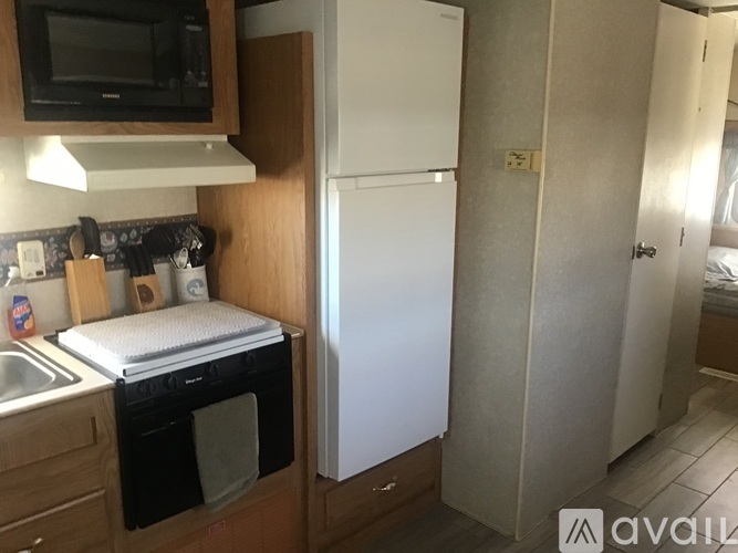 A kitchen with a white fridge, black oven, and wooden cabinets.