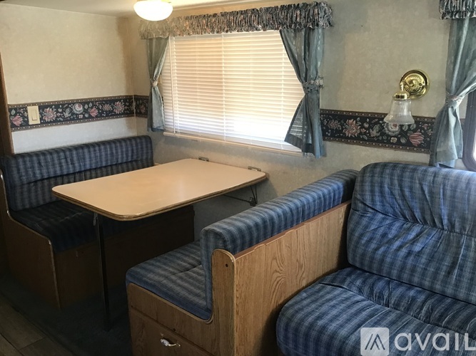 A blue couch sits in a room with a table and a window with curtains.
