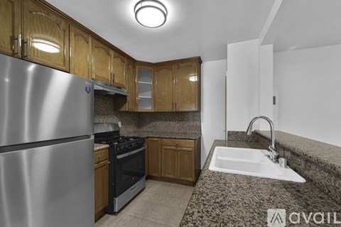 A kitchen with wooden cabinets and a stainless steel refrigerator.