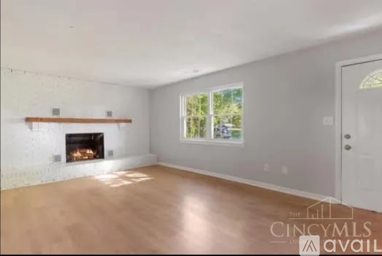 A large empty room with a fireplace and a window.