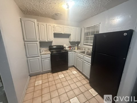 A kitchen with black appliances and white cabinets.