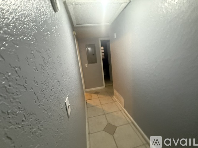 A hallway with a tiled floor and a door at the end.