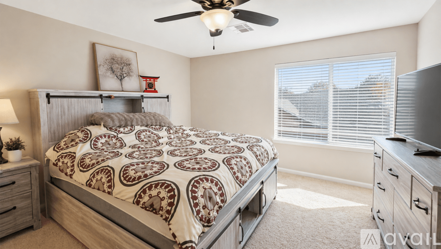 A bedroom with a bed, dresser, and ceiling fan.