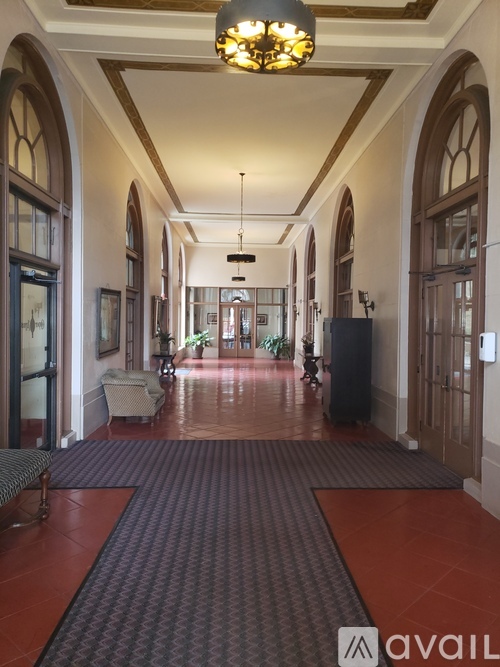 A hallway with a red carpet and a chandelier hanging from the ceiling.