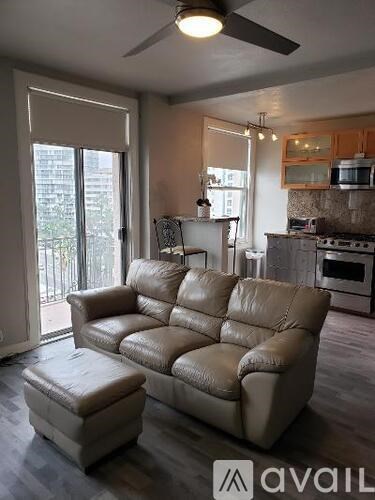 A living room with a brown leather couch and ottoman.