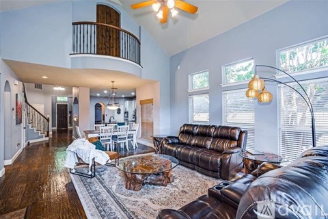 A living room with a brown leather couch and a wooden floor.