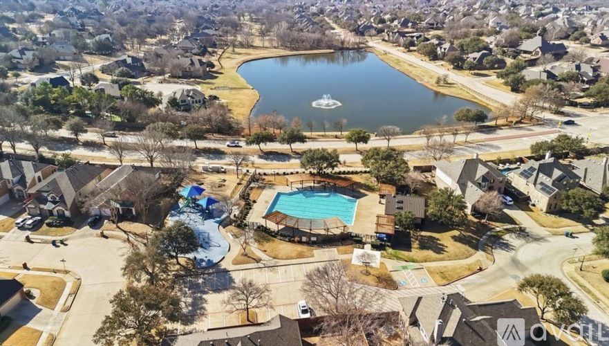 A bird's eye view of a residential area with a swimming pool and a lake.