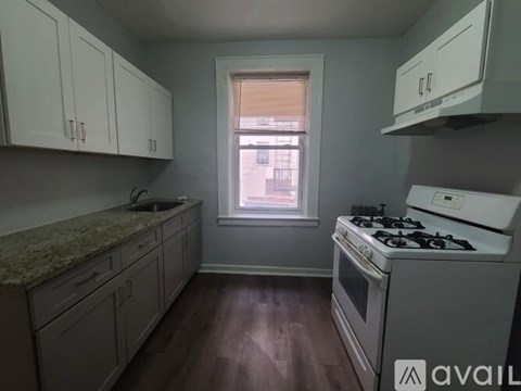 A kitchen with white cabinets and a window with blinds.