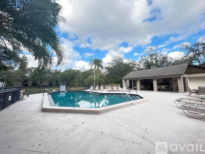 A swimming pool surrounded by a concrete patio and a house with a garage.