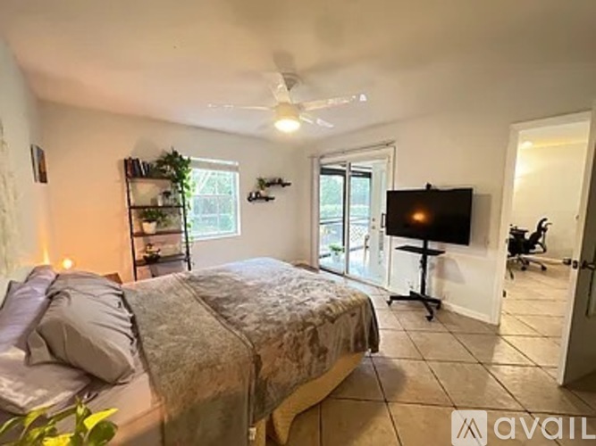 A bedroom with a bed, a television, and a ceiling fan.