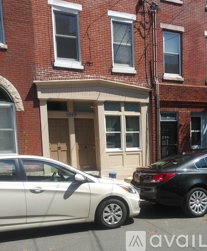 A white car is parked in front of a building with a sign that reads "avail.".